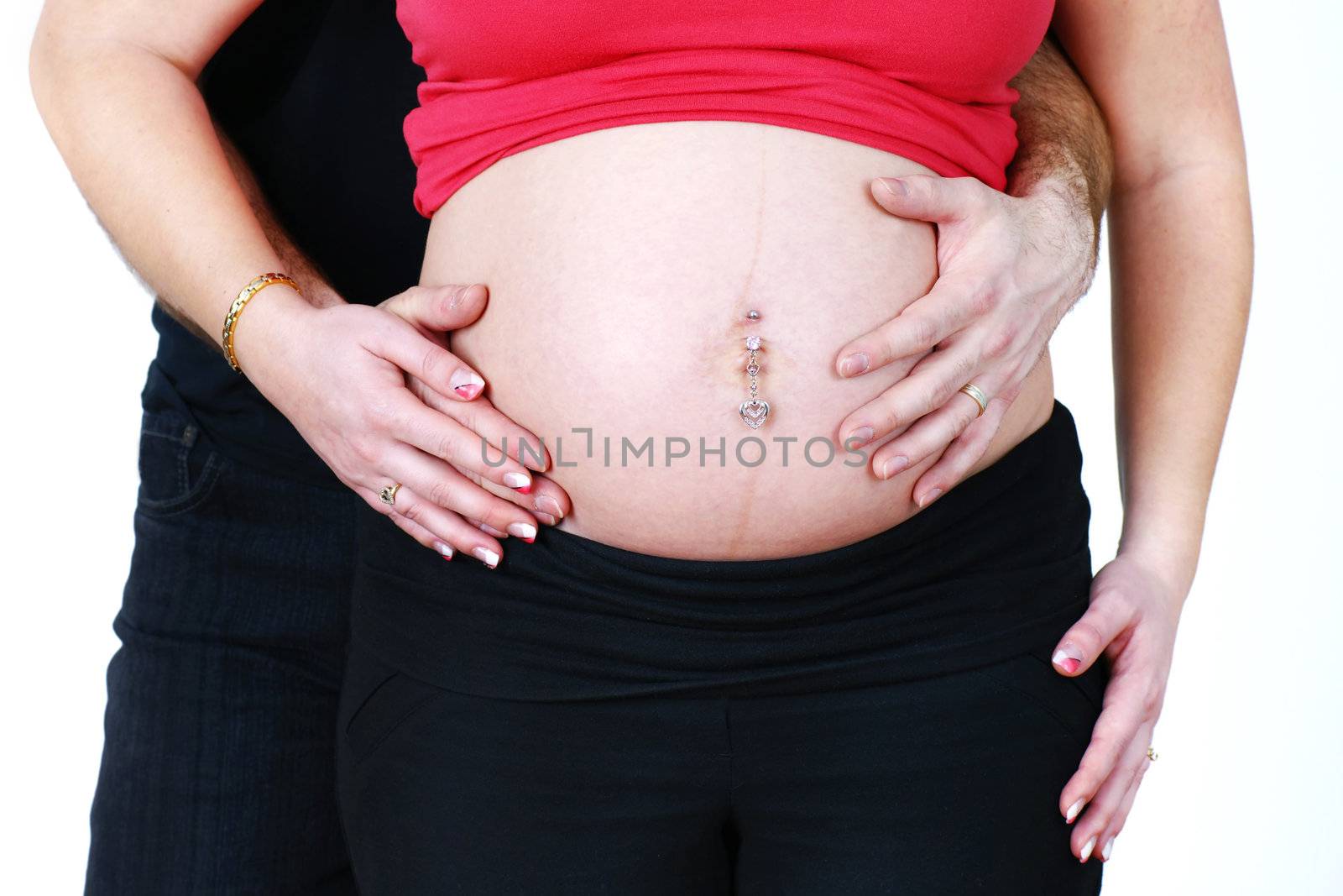 Pregnant couple, husband and wife cuddling and touching the belly, beautiful pregnancy studio shot over white.