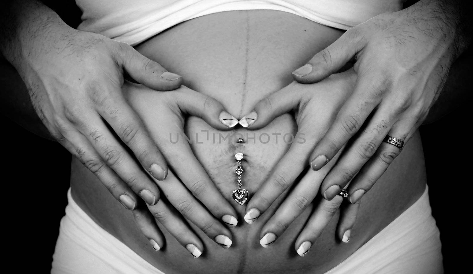 Young married couple making heart shapes with their hands over the woman's pregnant belly, beautiful love and family concept.