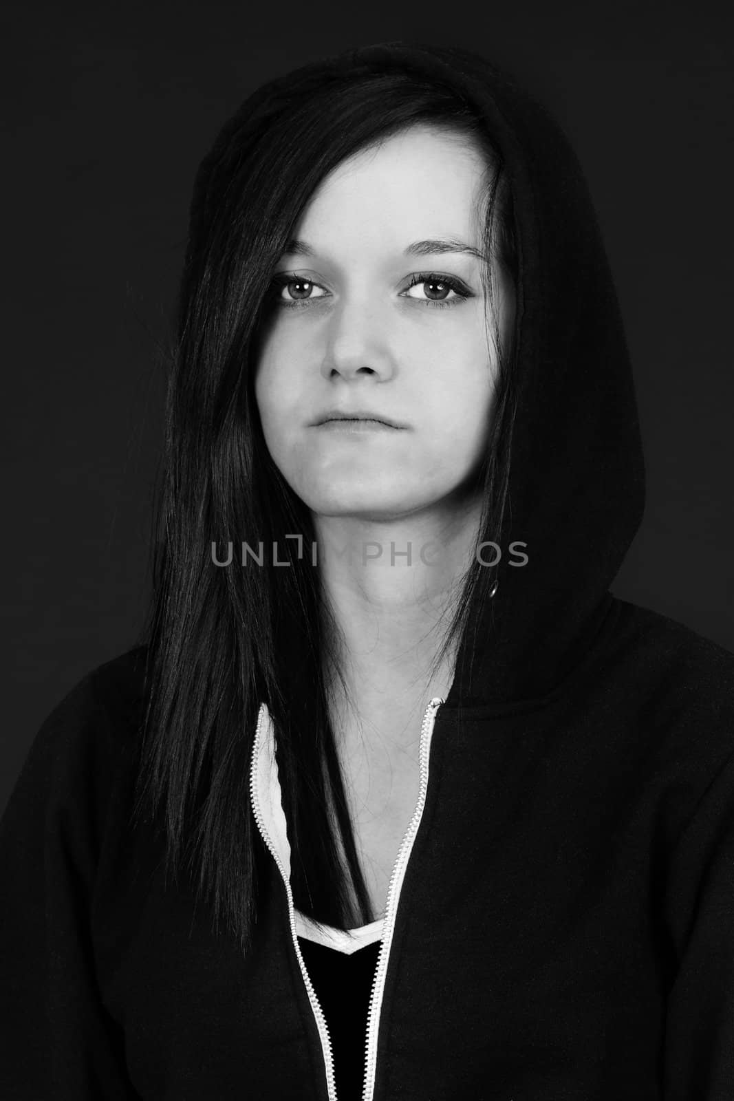 Black and white portrait of a young woman, teen or student looking sad or depressed, studio shot with black background.