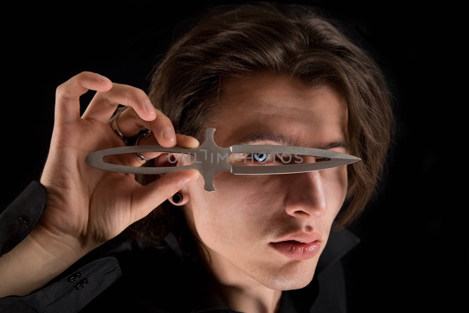 Handsome vampire looking through knife, Halloween theme 