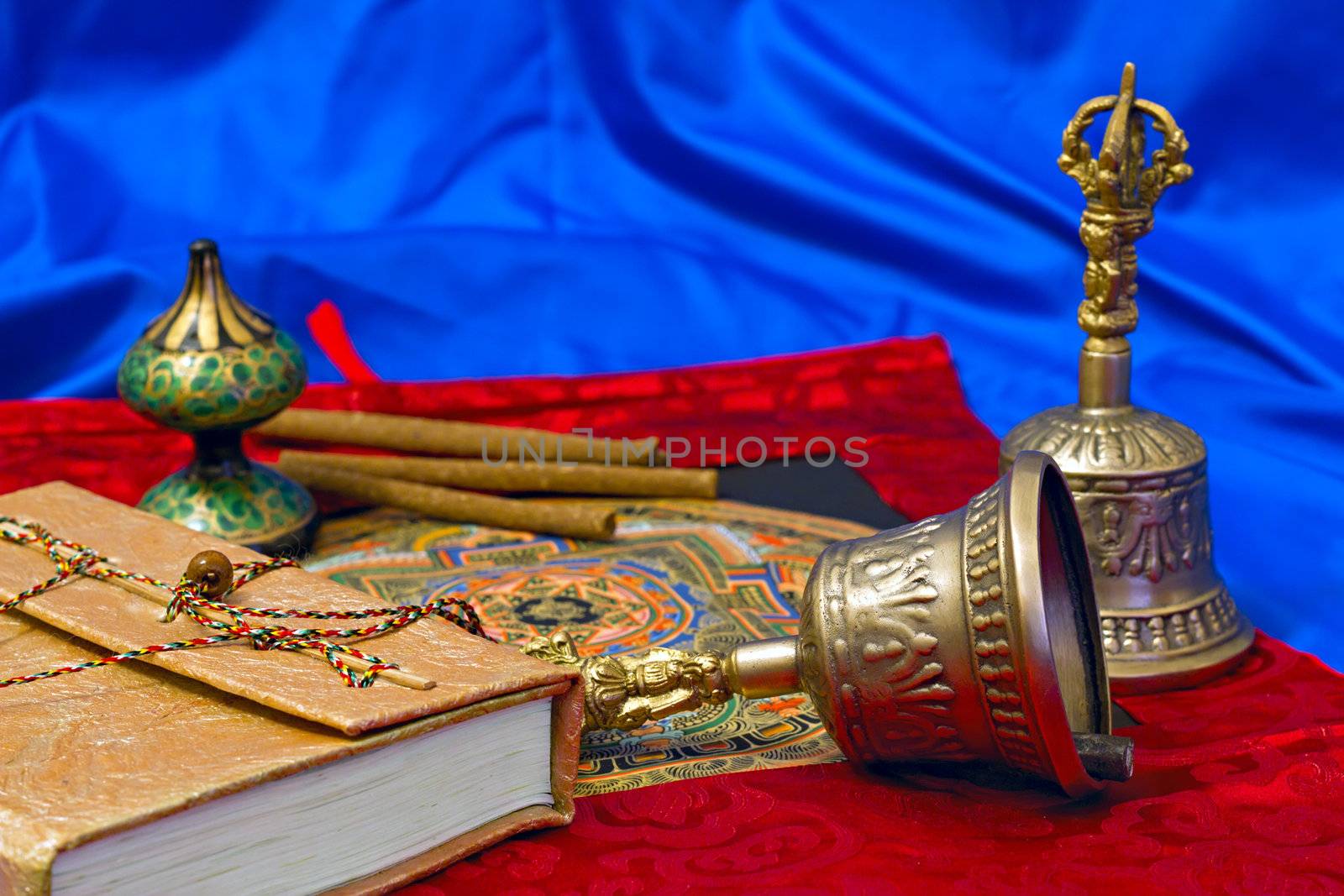 two Tibetan ritual bell and a book on a blue background