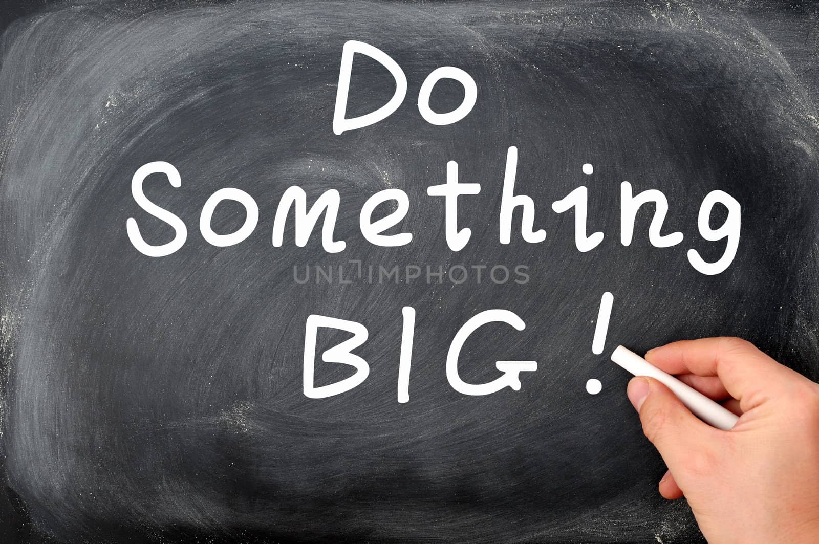Do something big written with chalk on a blackboard background, with a hand holding chalk