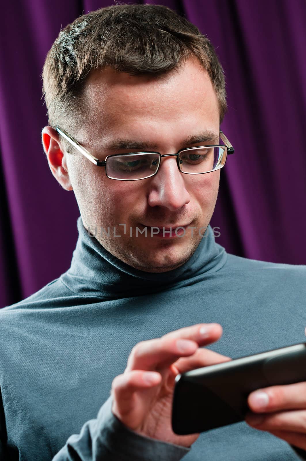 Man portrait with cellphone in arms with purple curtain on background