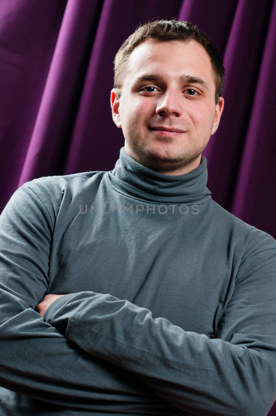 Man portrait with crossed arms with purple curtain on background