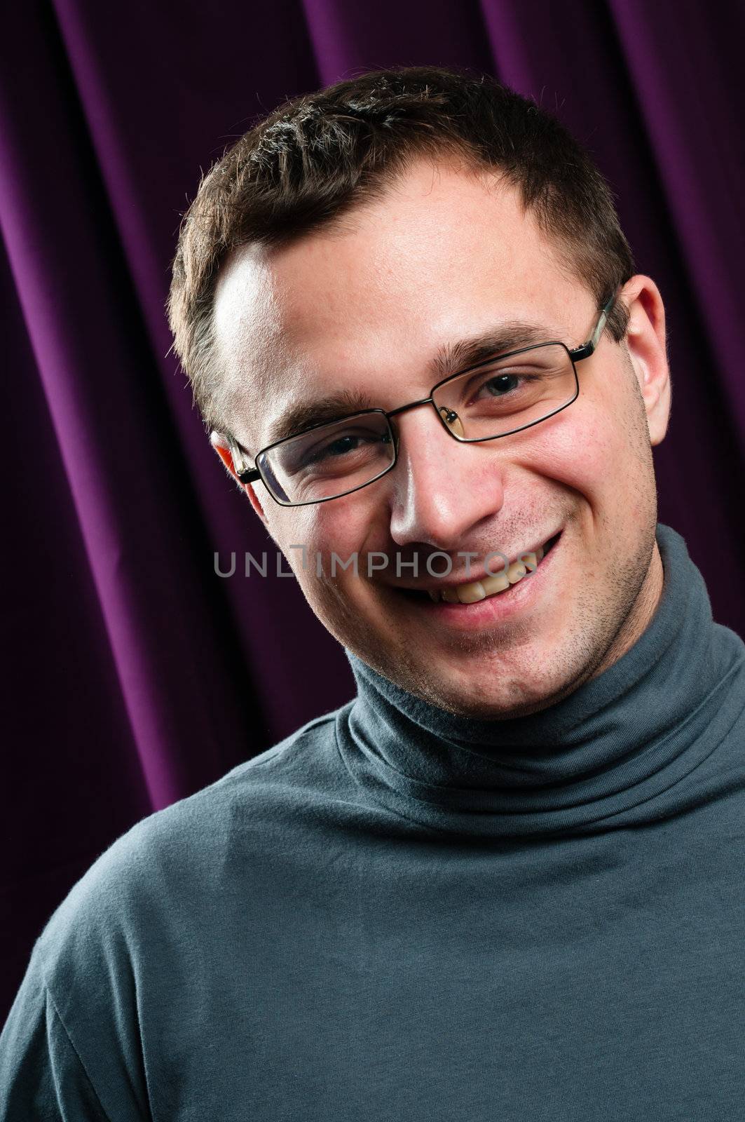 Smiling man with glasses portrait with purple curtain on background