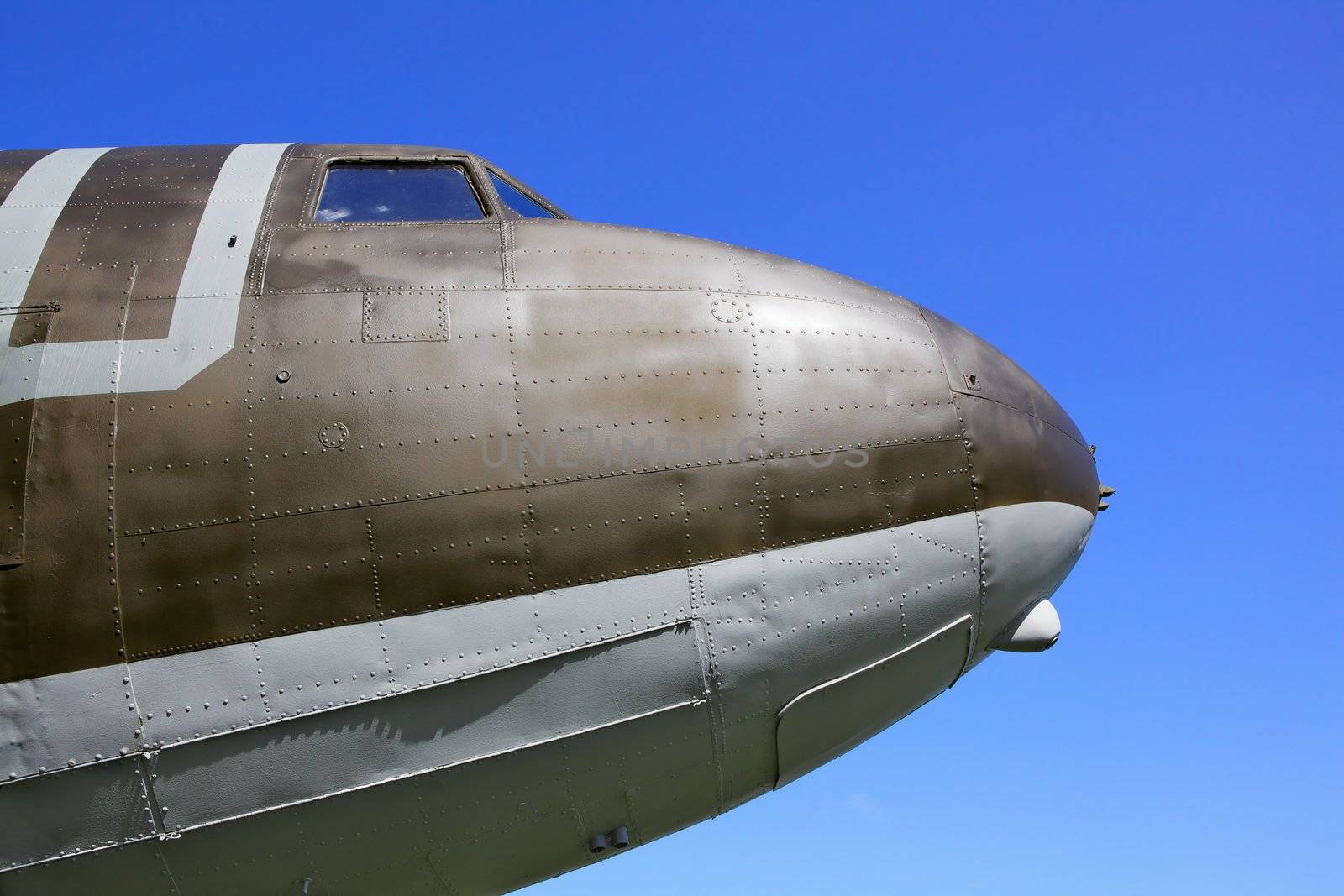WW II transport airplane nose showing dramatic contours with blue sky background