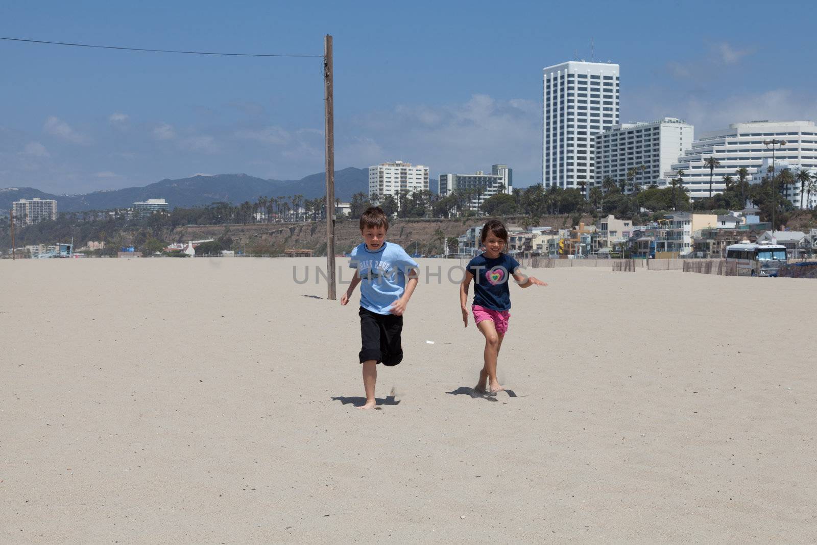 Little girl and boy running and racing in the sand on the beach.