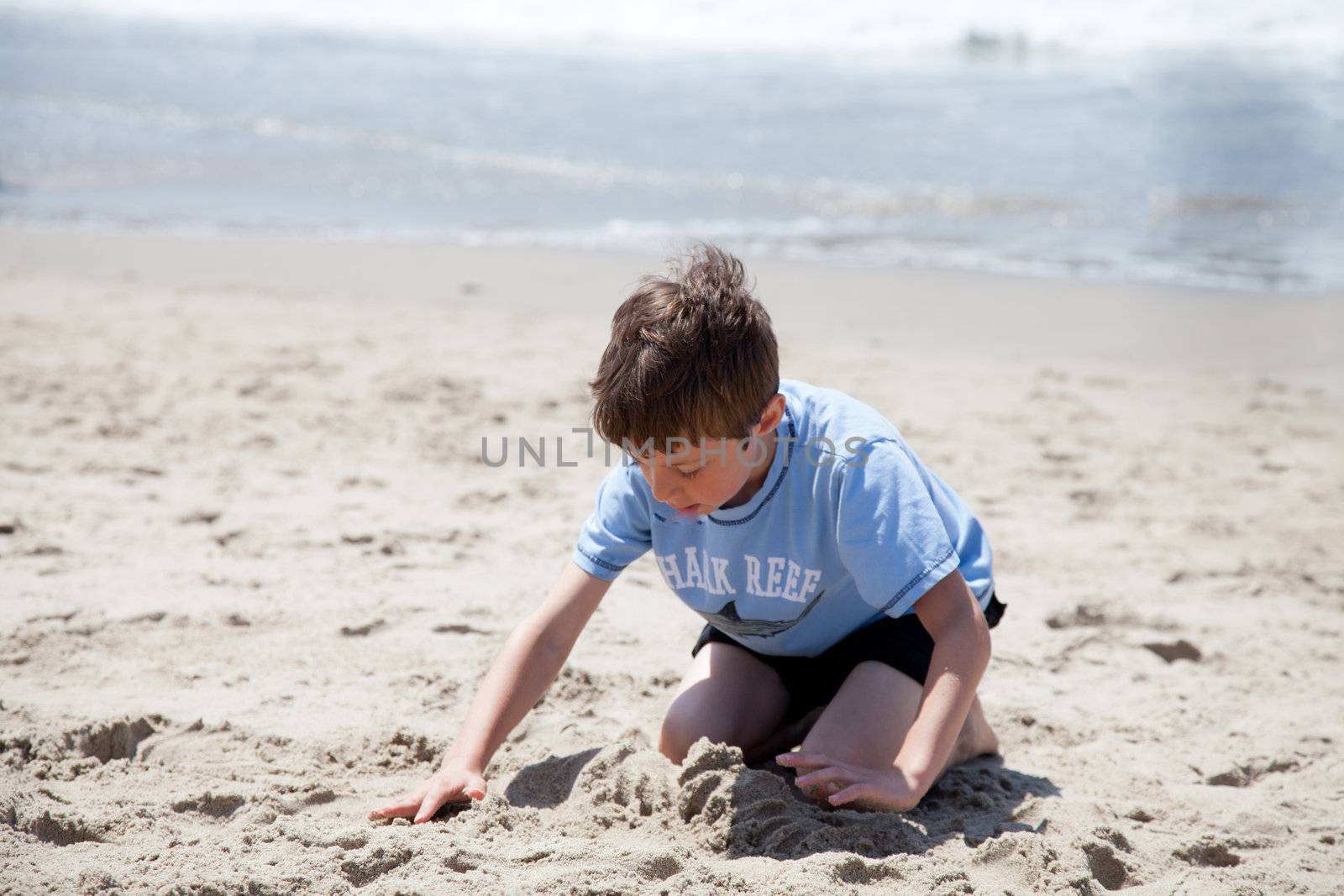 Little boy playing with sand on the beach.