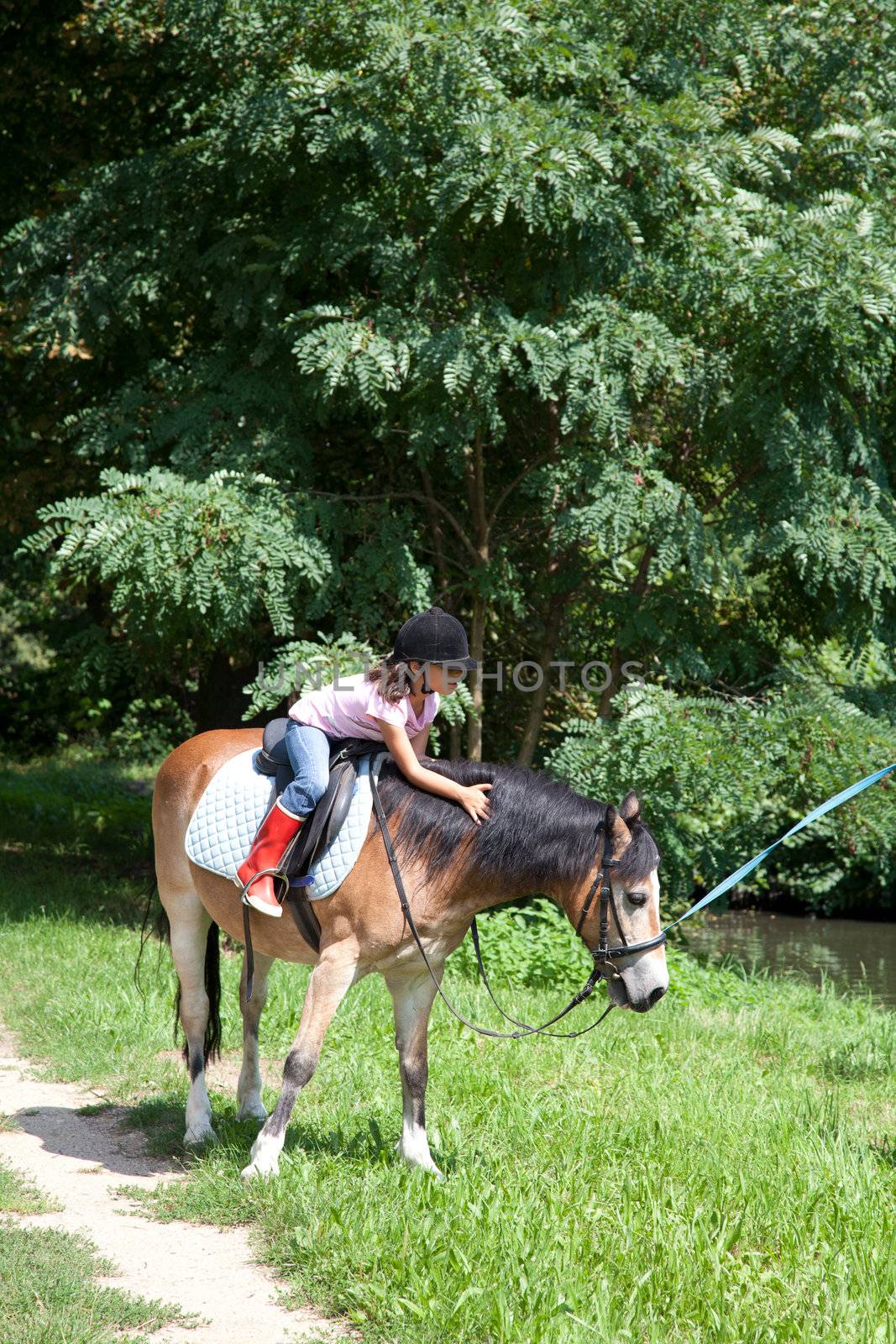 Little girl petting a horse while horseback riding by DashaRosato