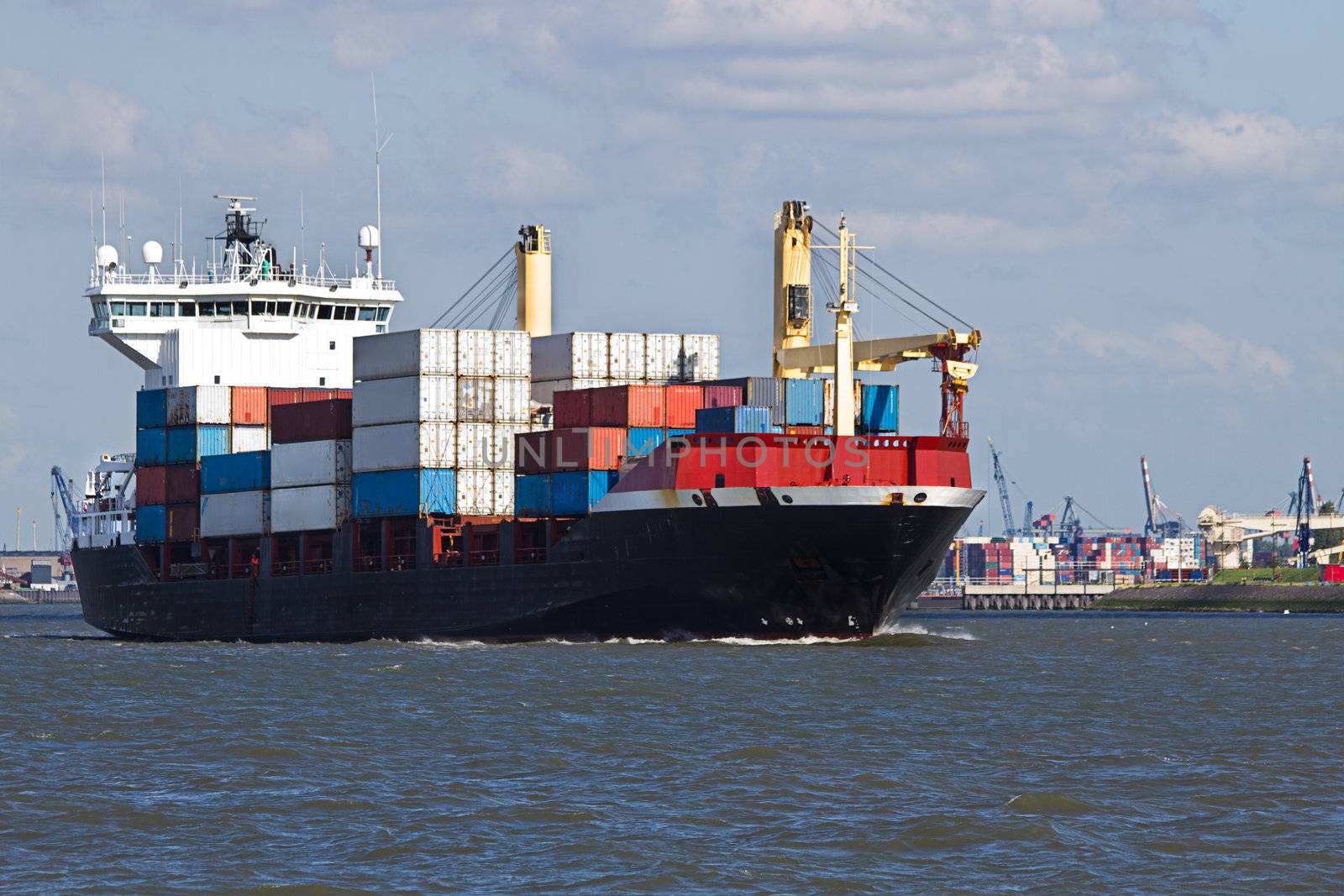 Containership leaving port with container harbor in background