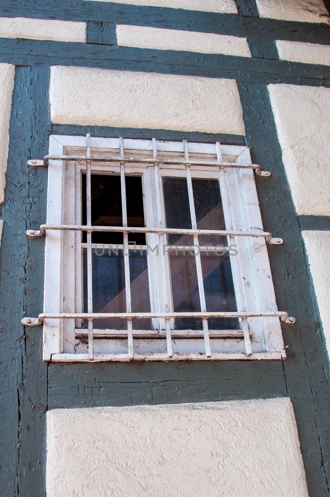 Old wooden framework facade of a half timbered house with barred window