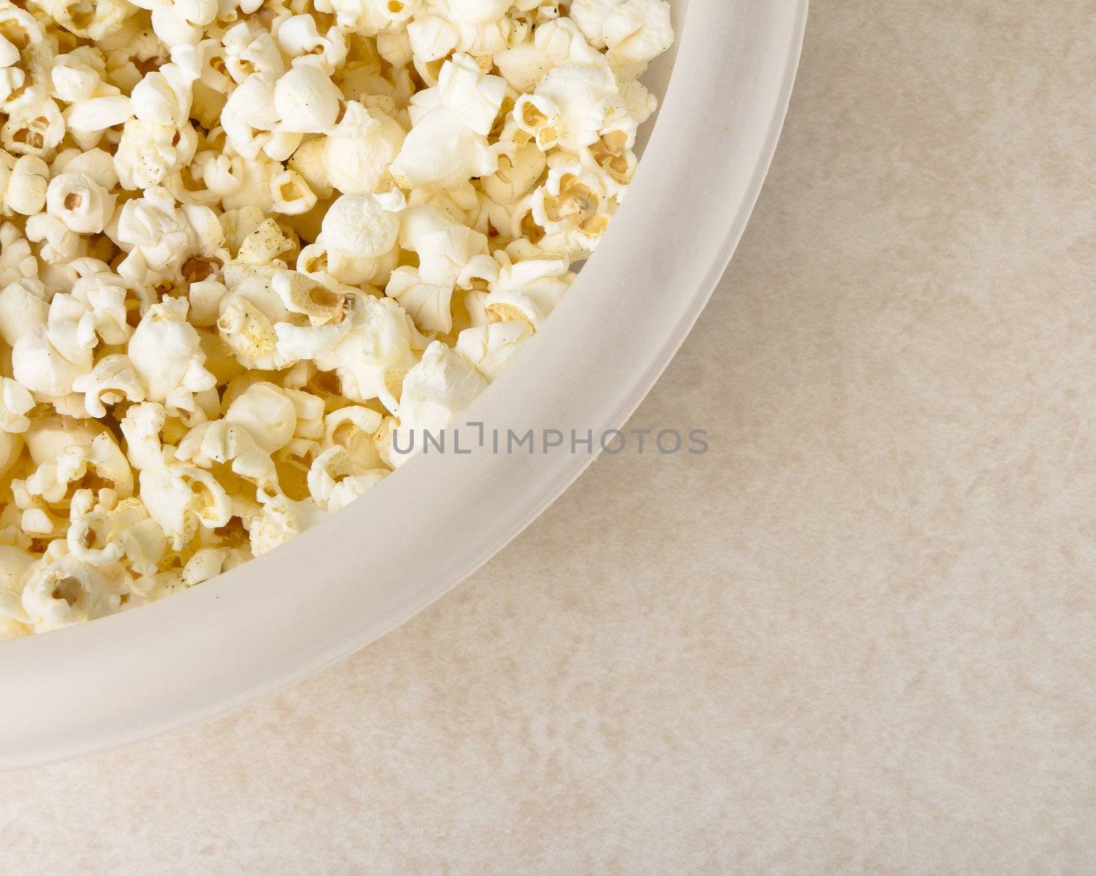 Bowl of buttered popcorn covering large portion of frame with copyspace in lower left