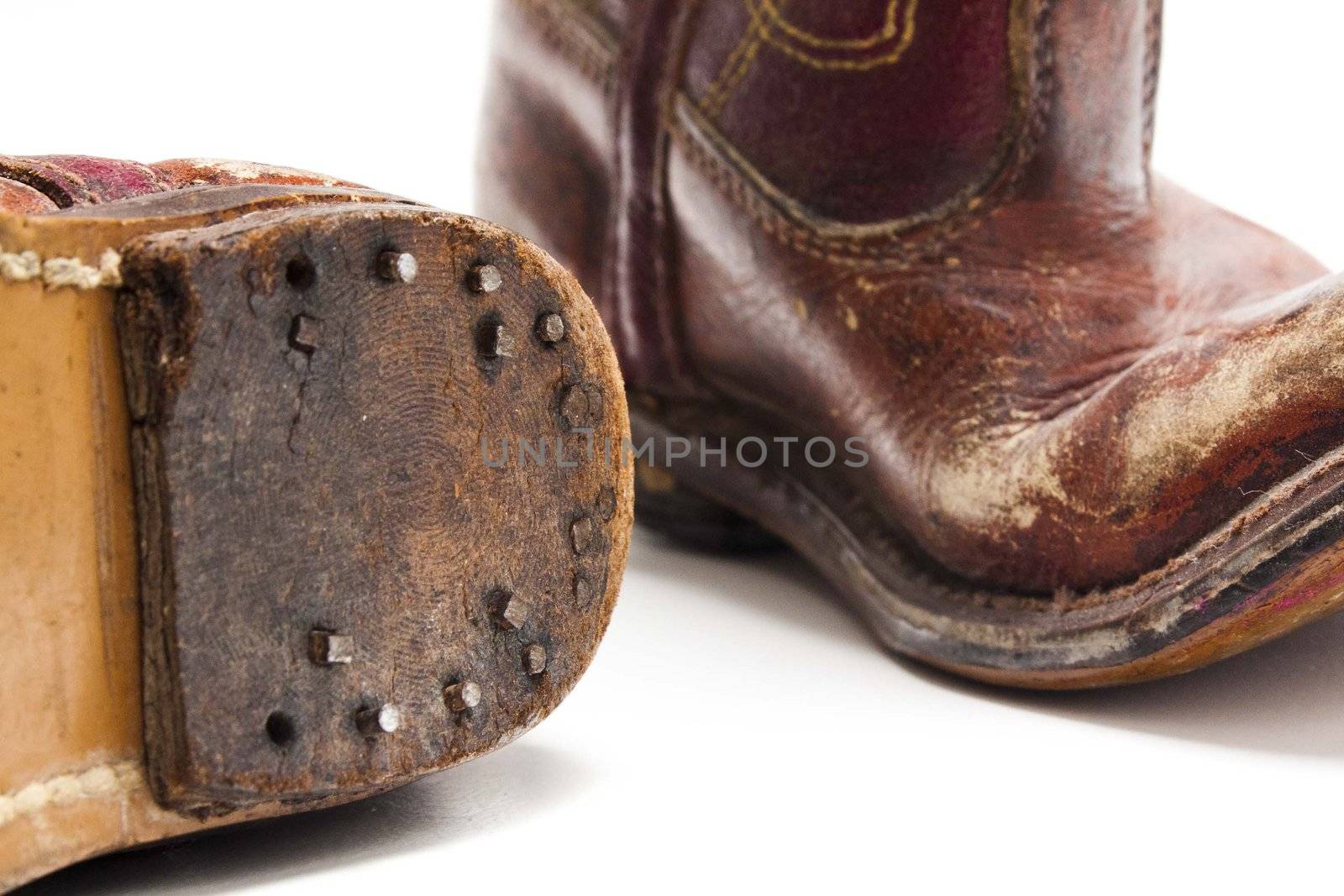 Old worn out pare of cowboy boots from someones childhood days against a white background