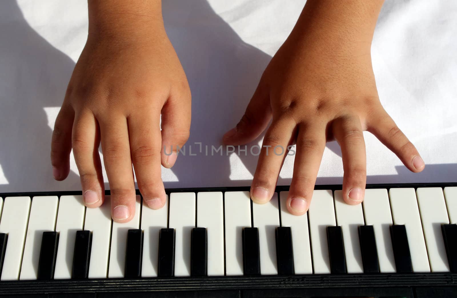 Child hands playing portable musical instrument 
