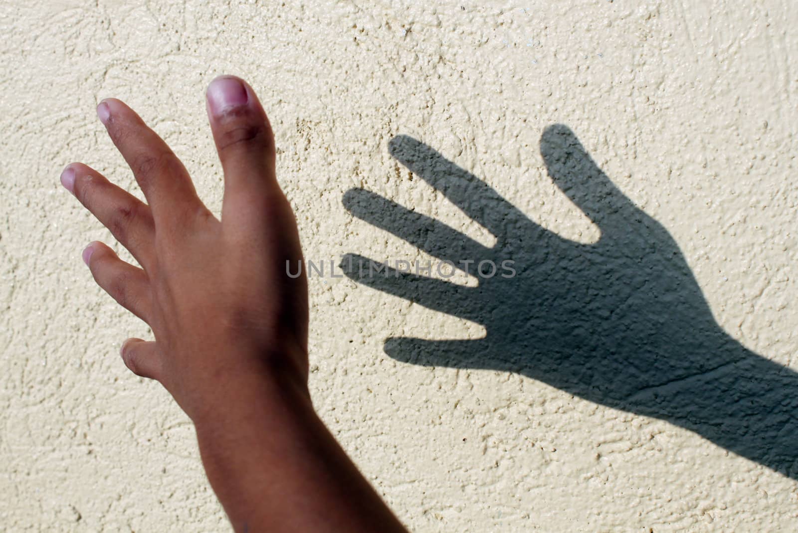Child hand's shadow against the concete wall