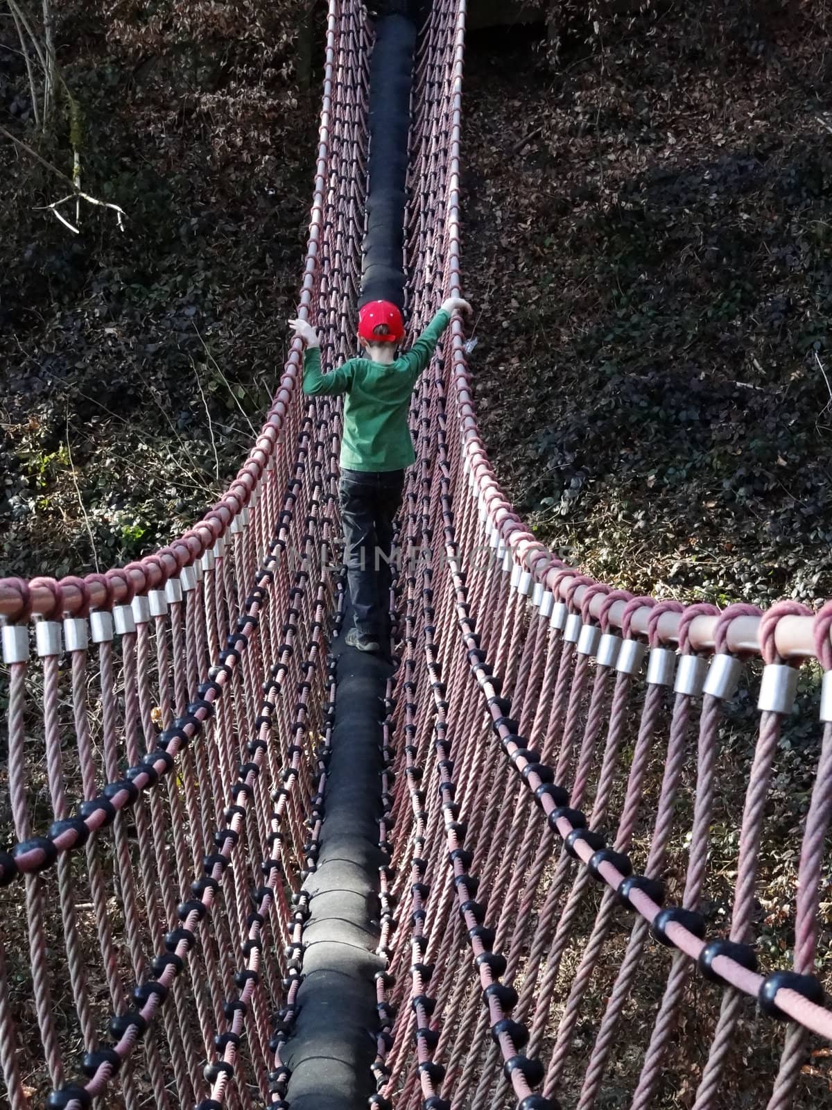 A boy walks on a swing bridge