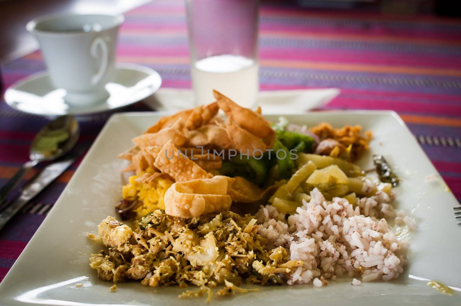 Traditional Sri Lankian food with rice, chicken with coconut, vegetables. Ginger drink and tea.
