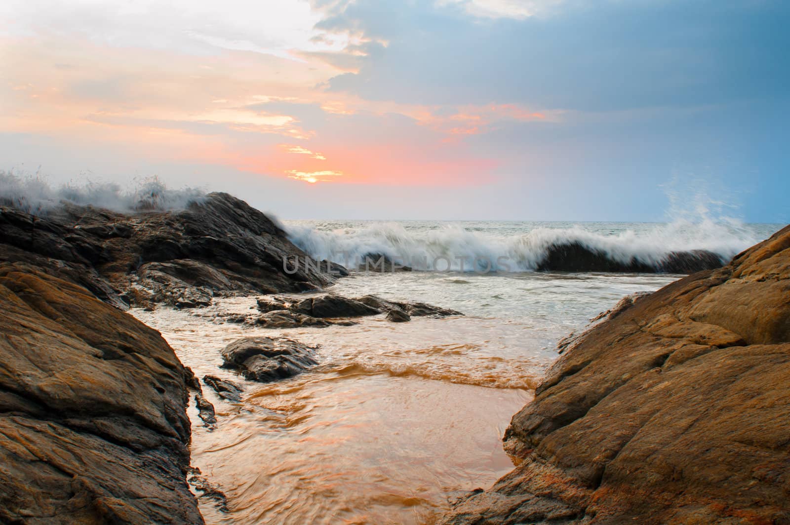 Beautiful stones and waves at sunset under blue sky