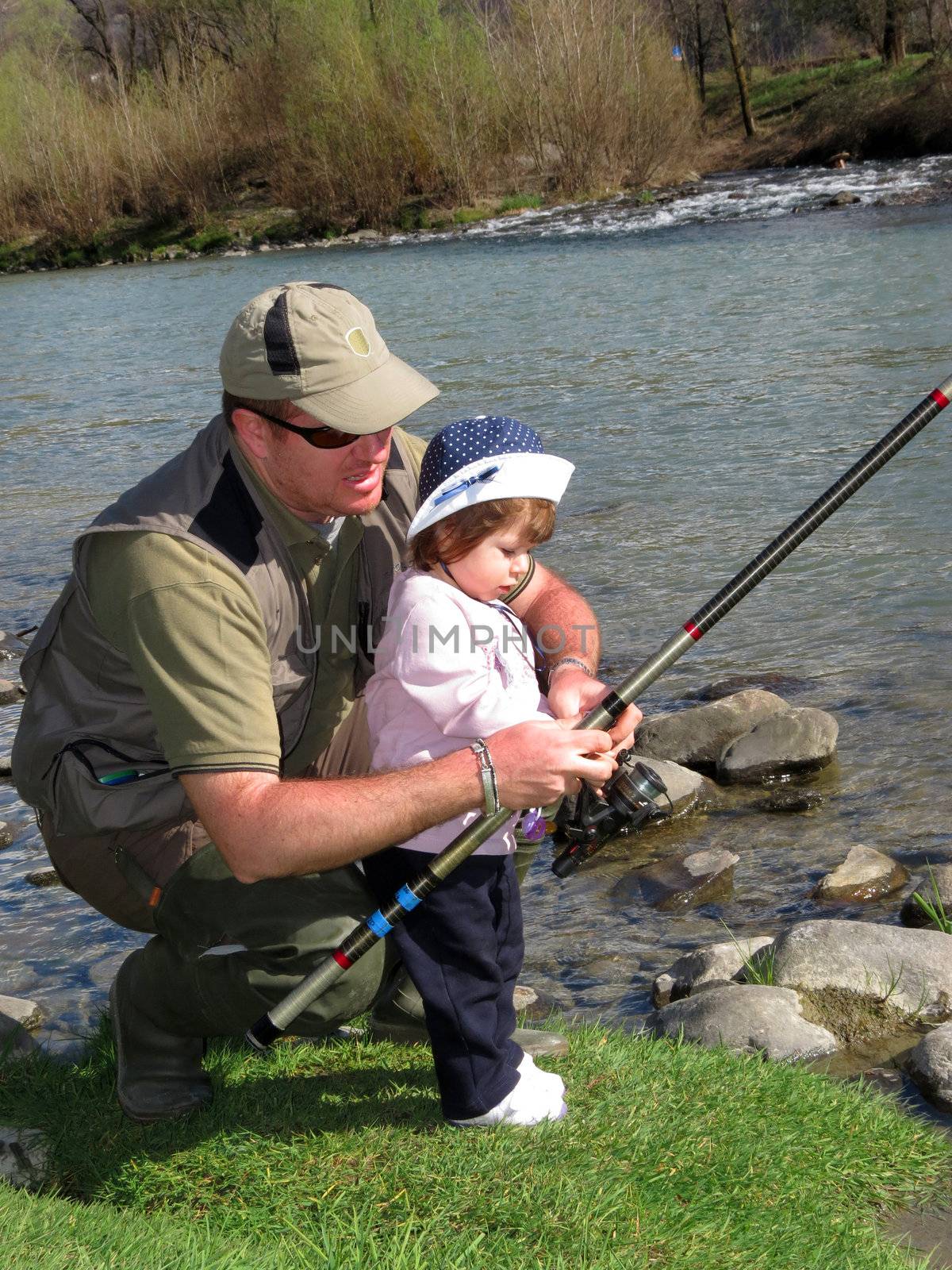 father and daughter fishing on river on summer day 