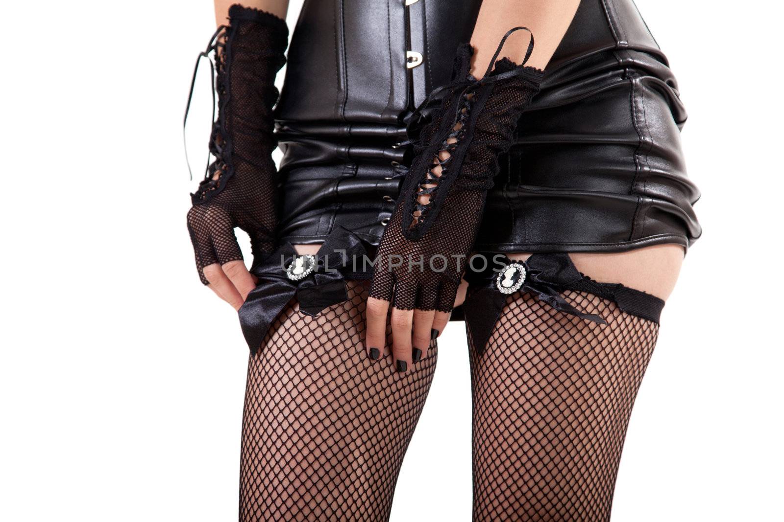 Woman dressed in leather dress putting on fishnet stockings, isolated on white background 