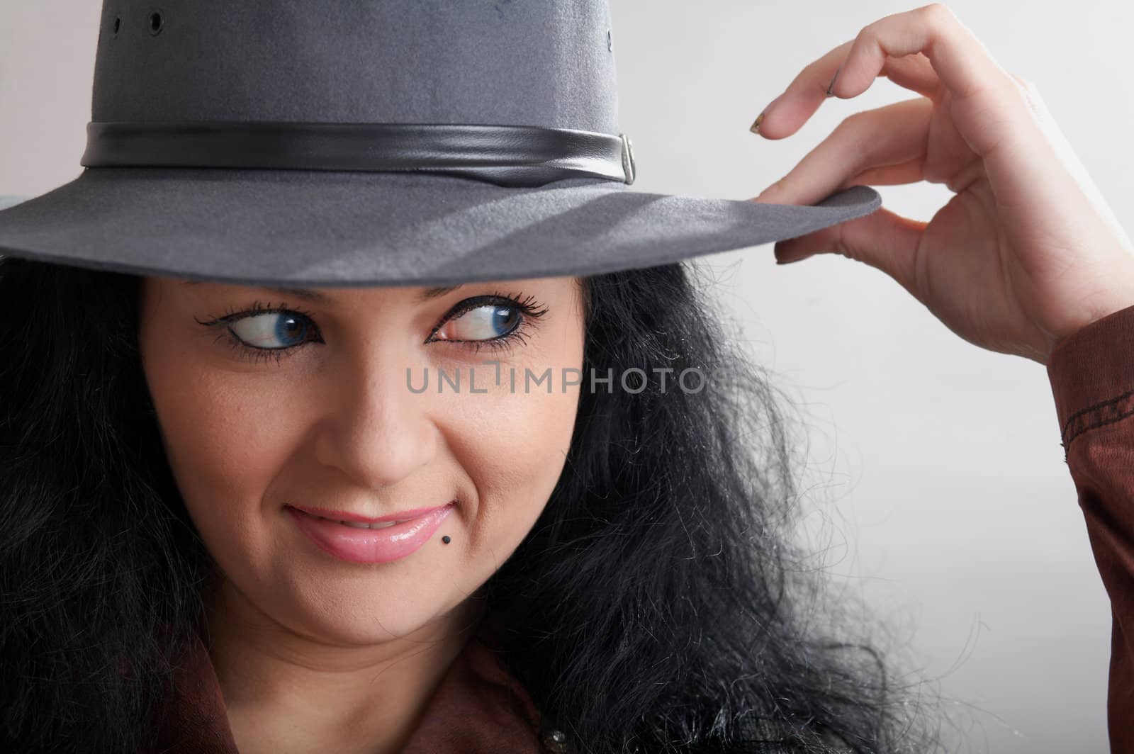 A smiling girl trying on a grey hat