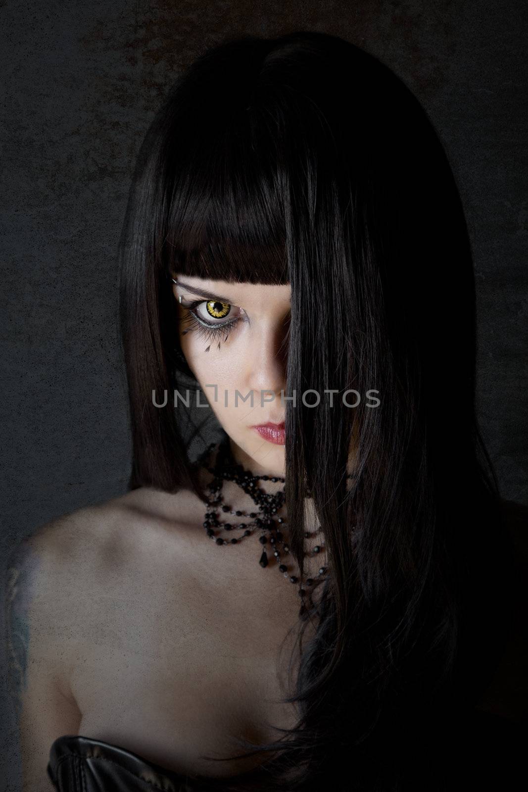 Young witch with yellow eyes and black long hair, textured background 