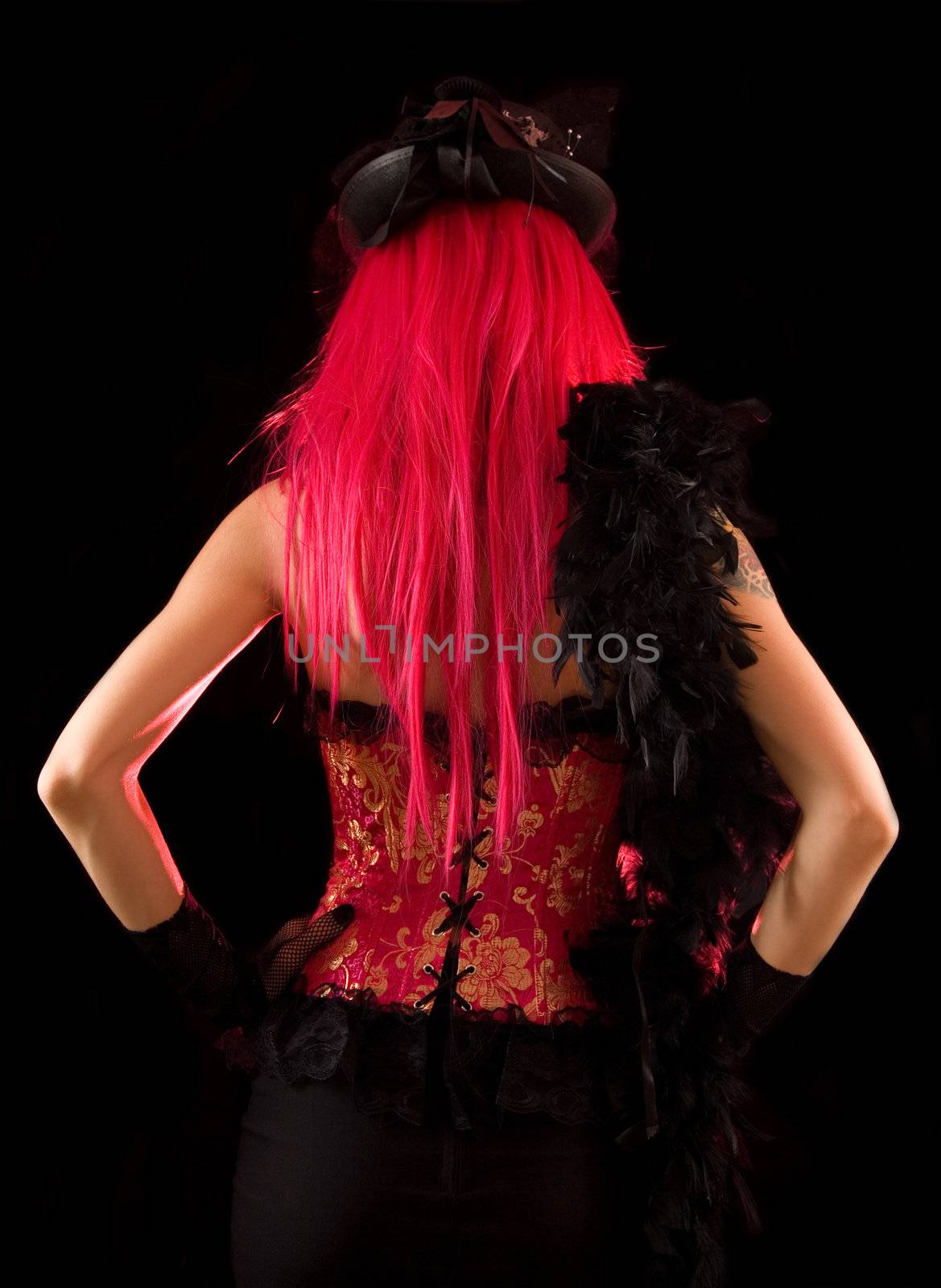 Rear view of cabaret girl in pink corset with feather boa, isolated on black background  