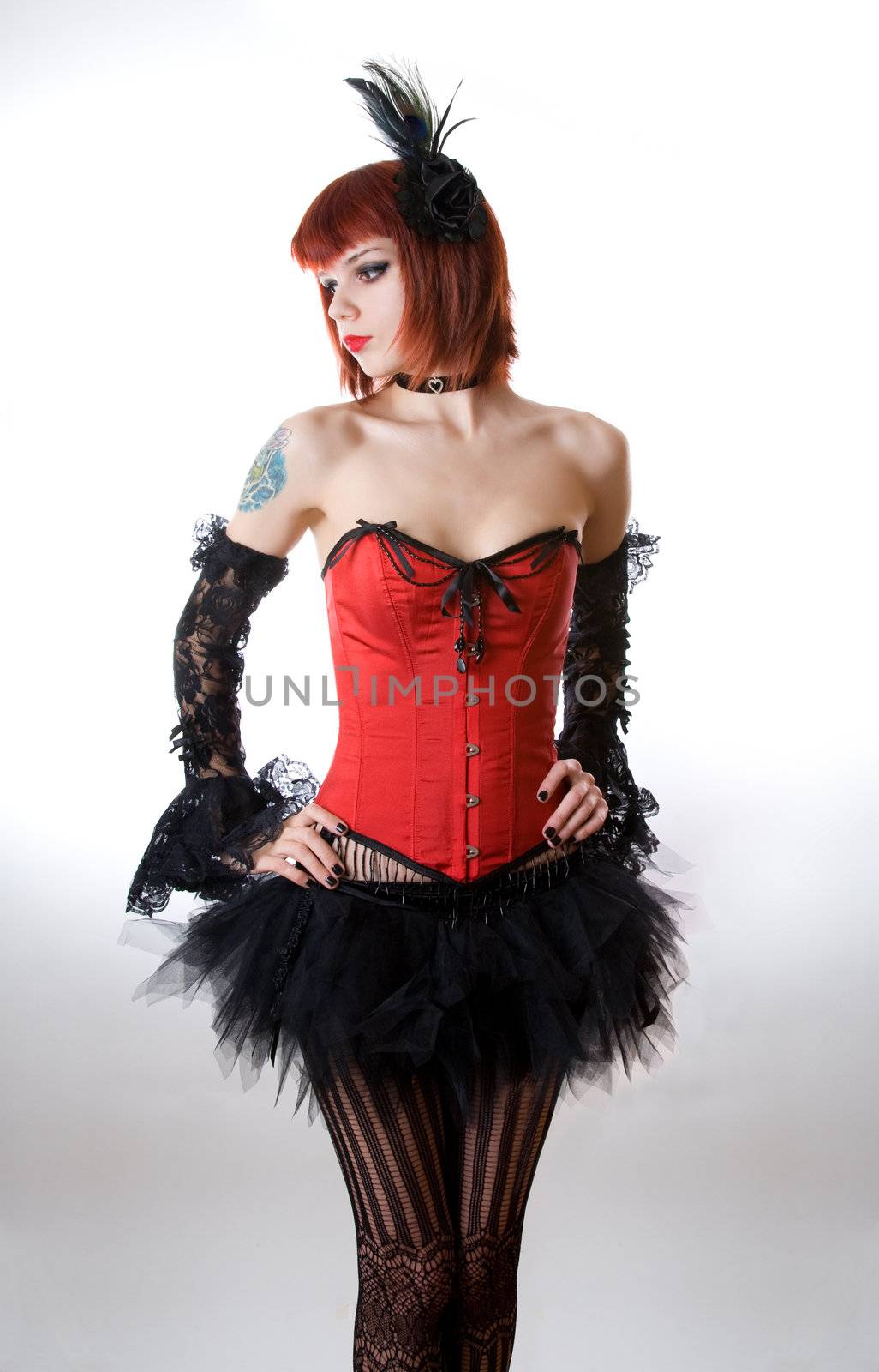 Attractive woman in red corset and black skirt, studio shot over white background 