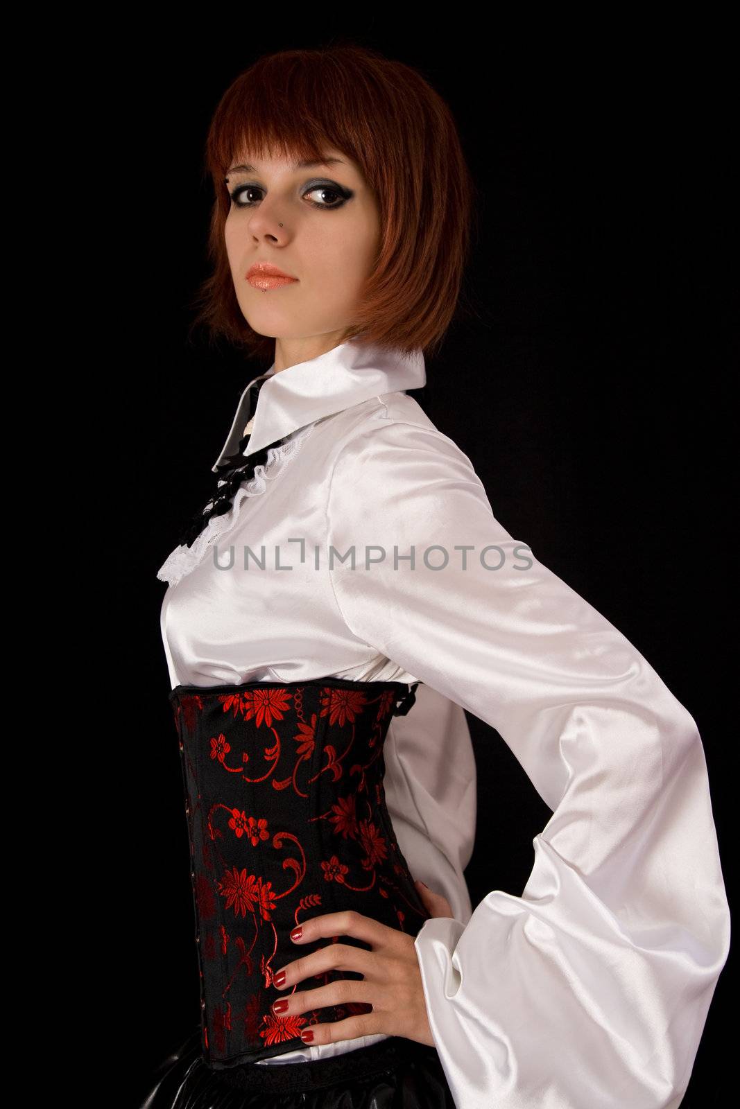 Attractive girl in white blouse with long sleeves and corset, isolated on black background 