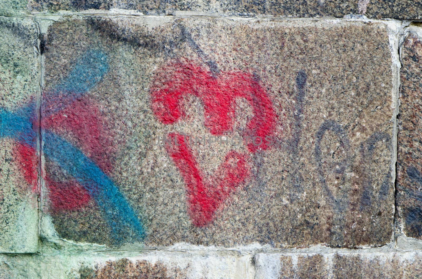 Red heart painted on ancient stone block wall background.