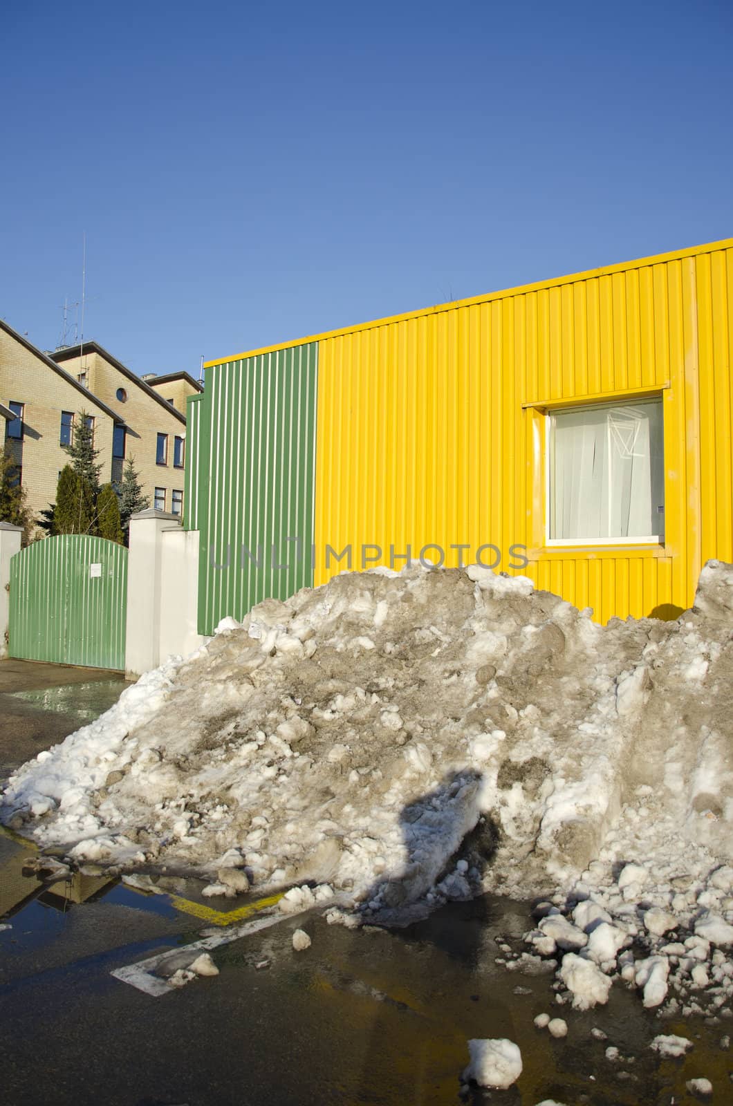 pile of melting snow in spring near building by sauletas