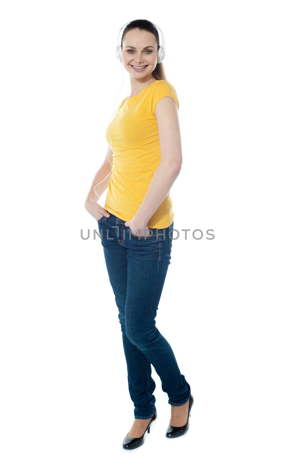 Stylish teenager enjoying music and posing with hands in pocket