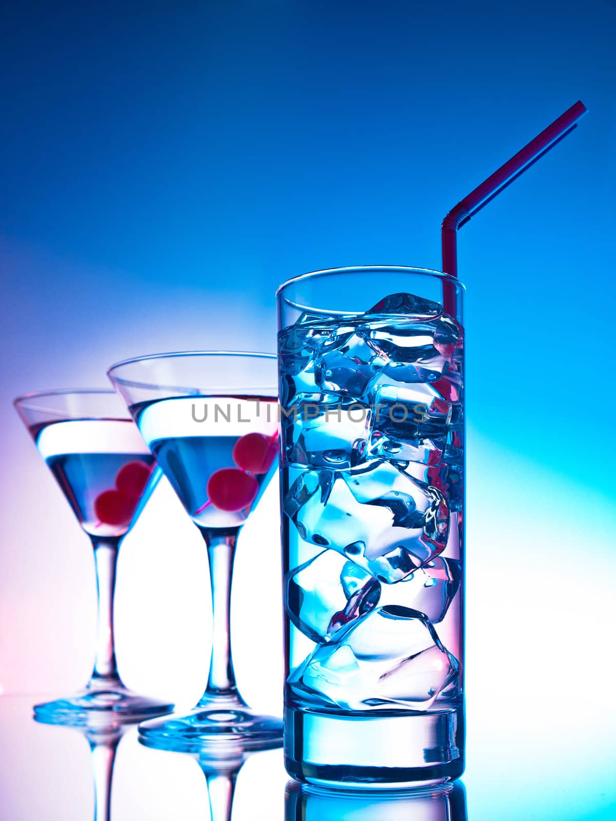 Two glasses of martini with red cherries and a glass of clear cocktail