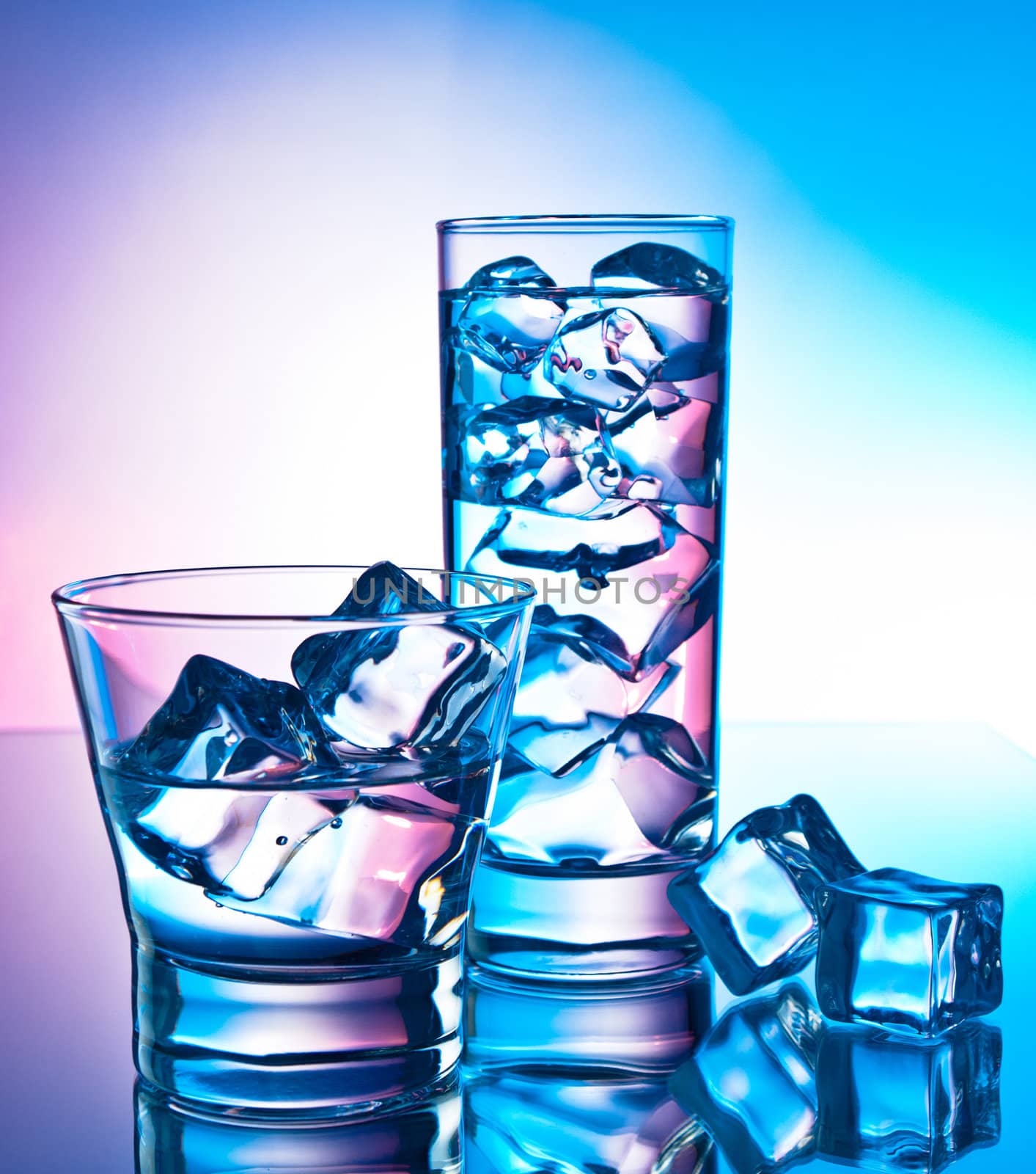 Two cocktails on a reflective surface with ice cubes