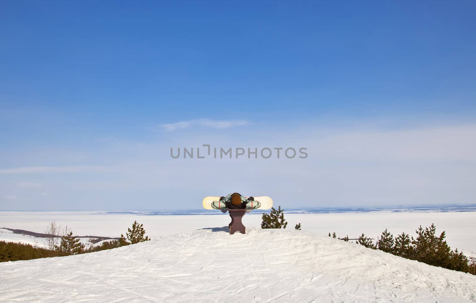 Snowboarder lies on the bench. Against the backdrop of beautiful mountain  landscape of winter. A sunny day.
