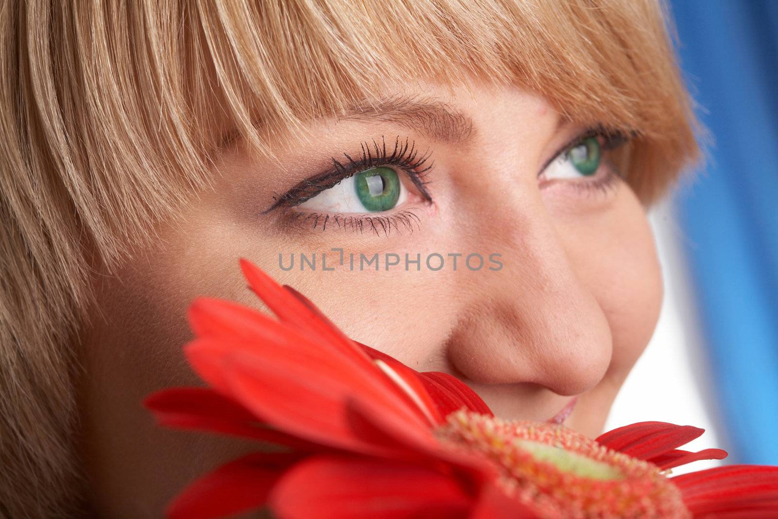 Girl's green eyes and a red flower close-up