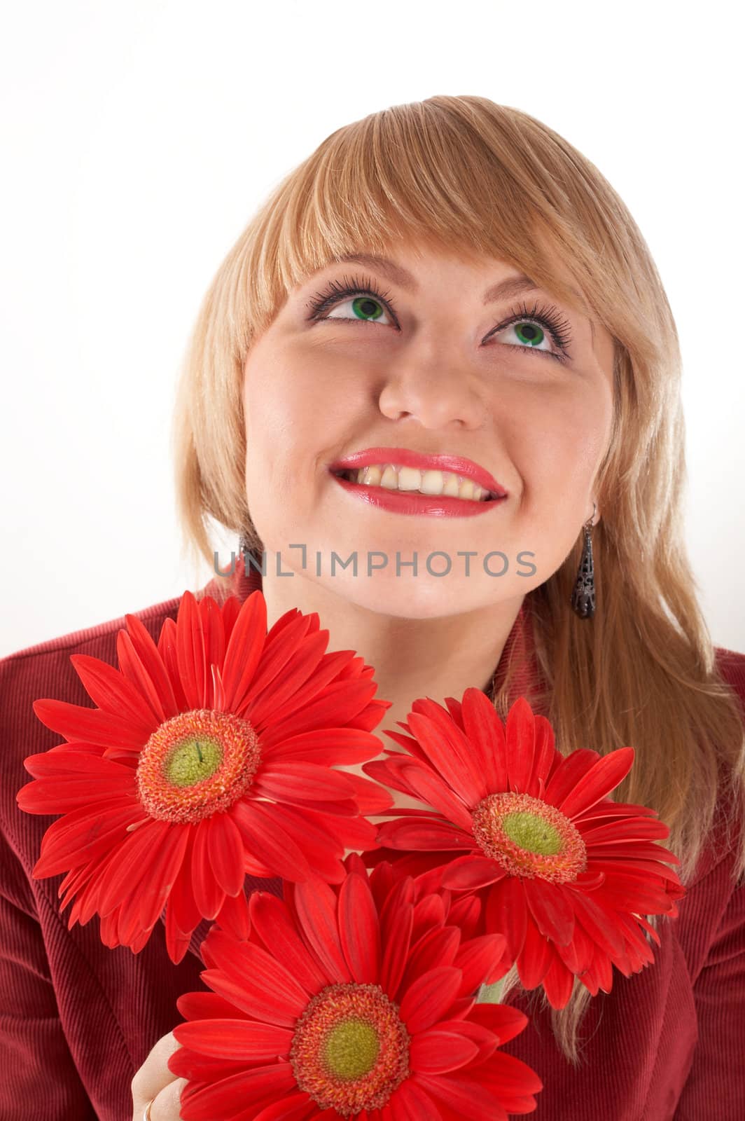 A smiling girl with red flowers looking up