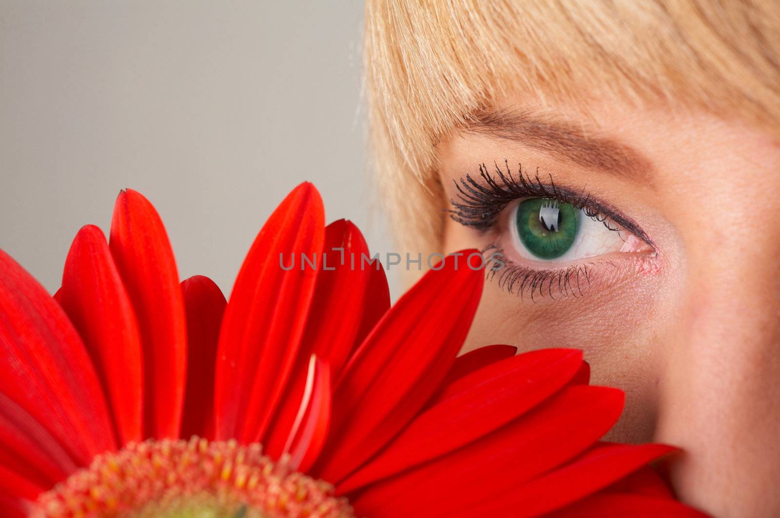 Girl's green eye and a red flower close-up