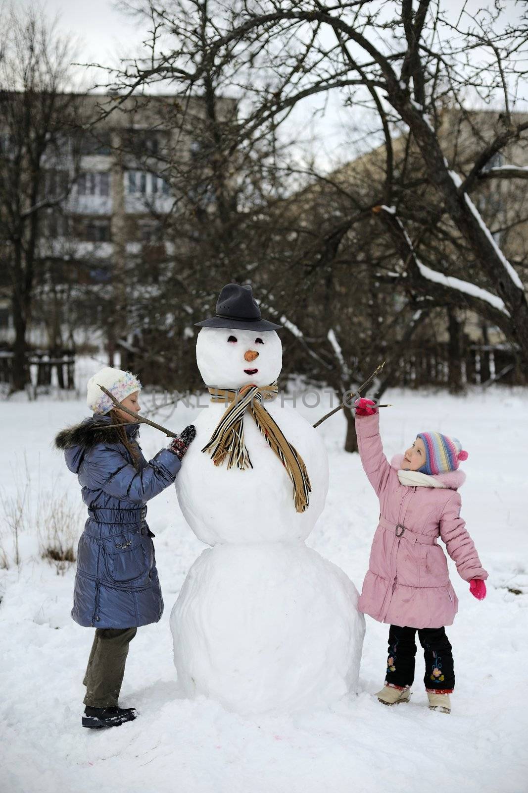 Two little girls are doing big snowman