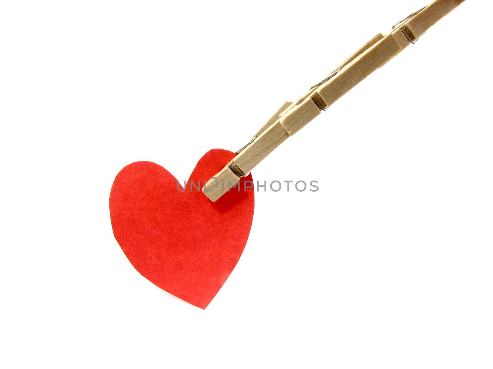 Wooden pins pinch red heart on white background