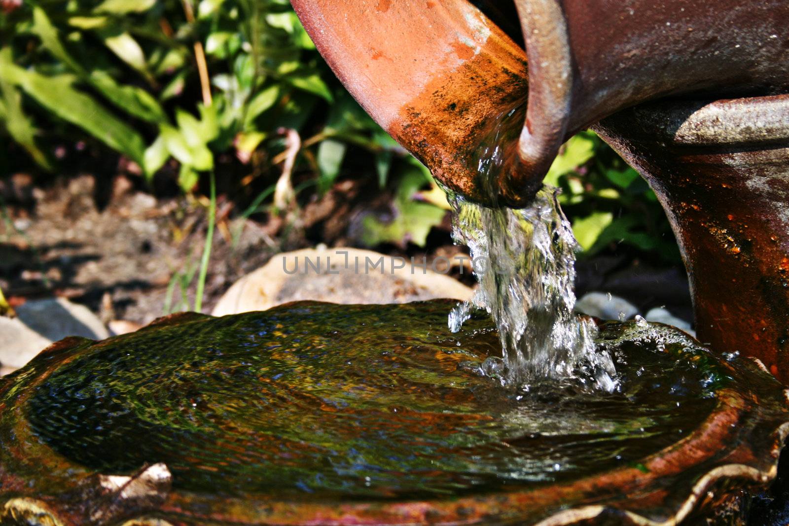 Old earthenware jug pouring water