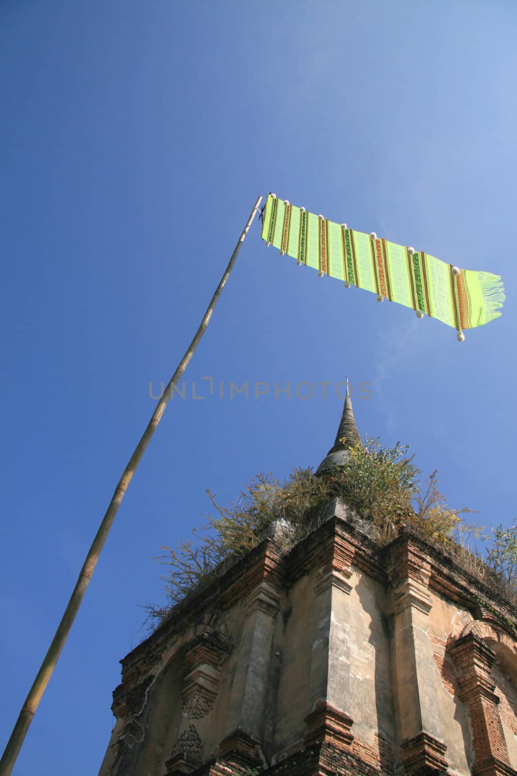 Old pagoda and green lanna flag with blue sky