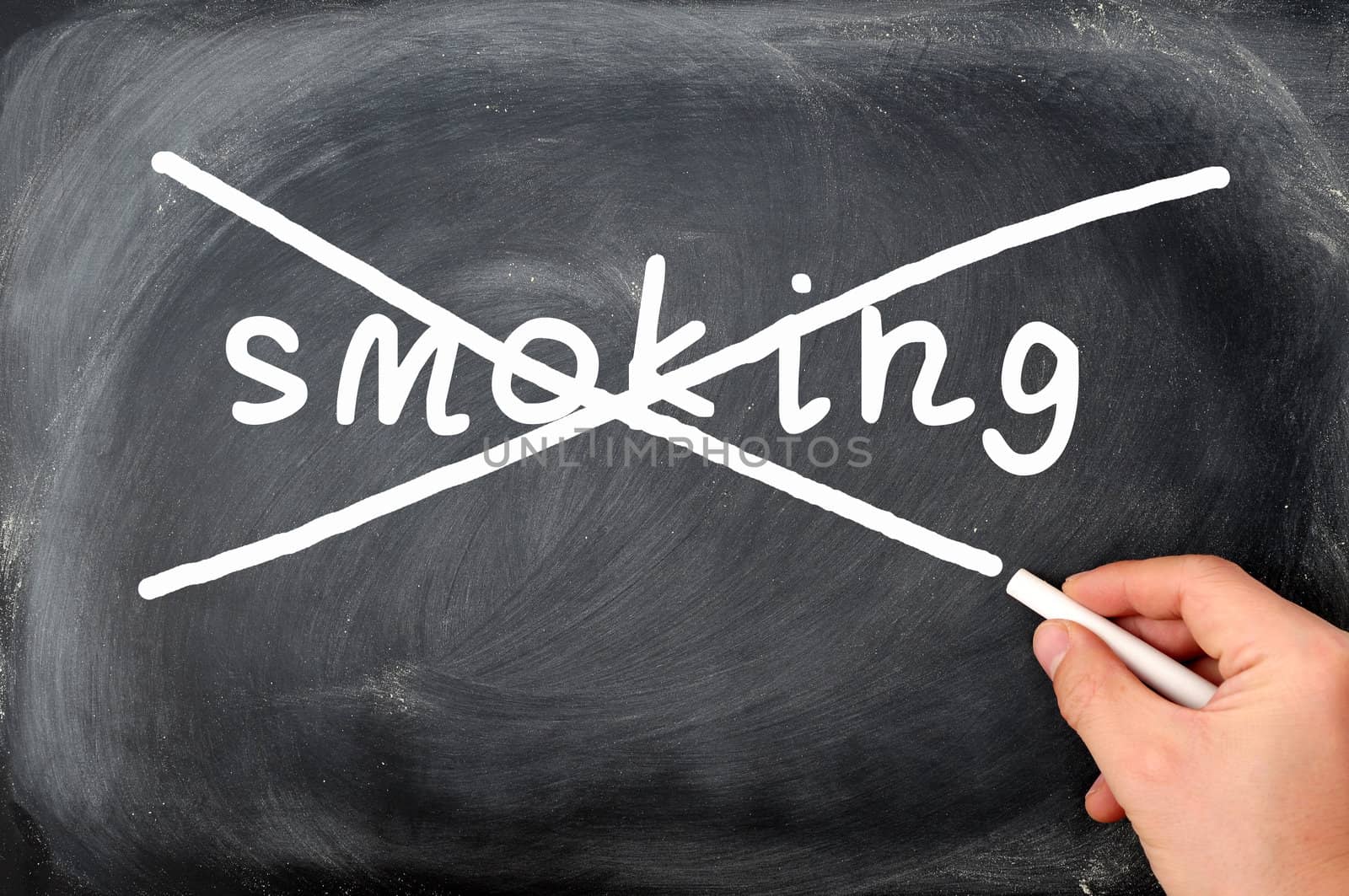 No smoking concept on a blackboard, crossing out with a hand holding chalk
