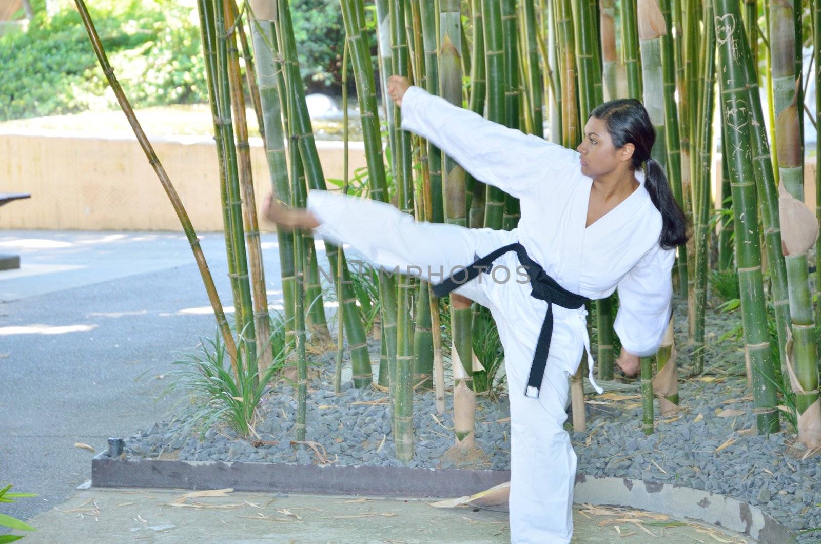 Female black belt champion karate player demonstrating various karate moves in the park