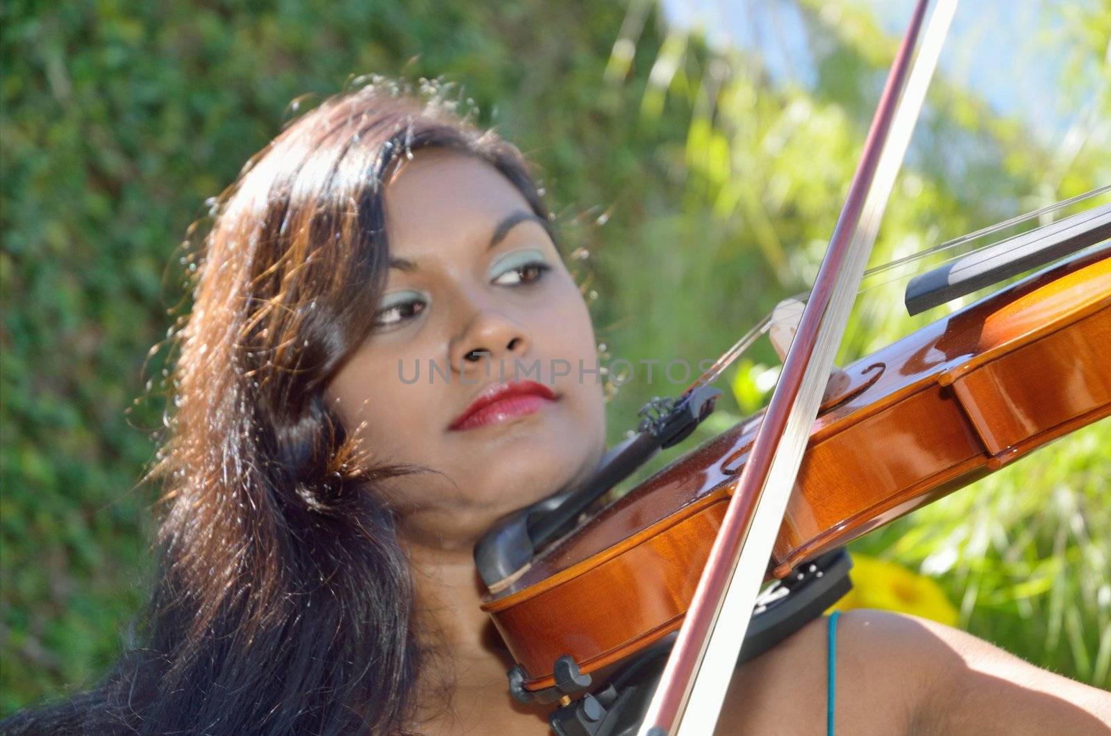 Attractive brunette musician providing live music in the park on her violin