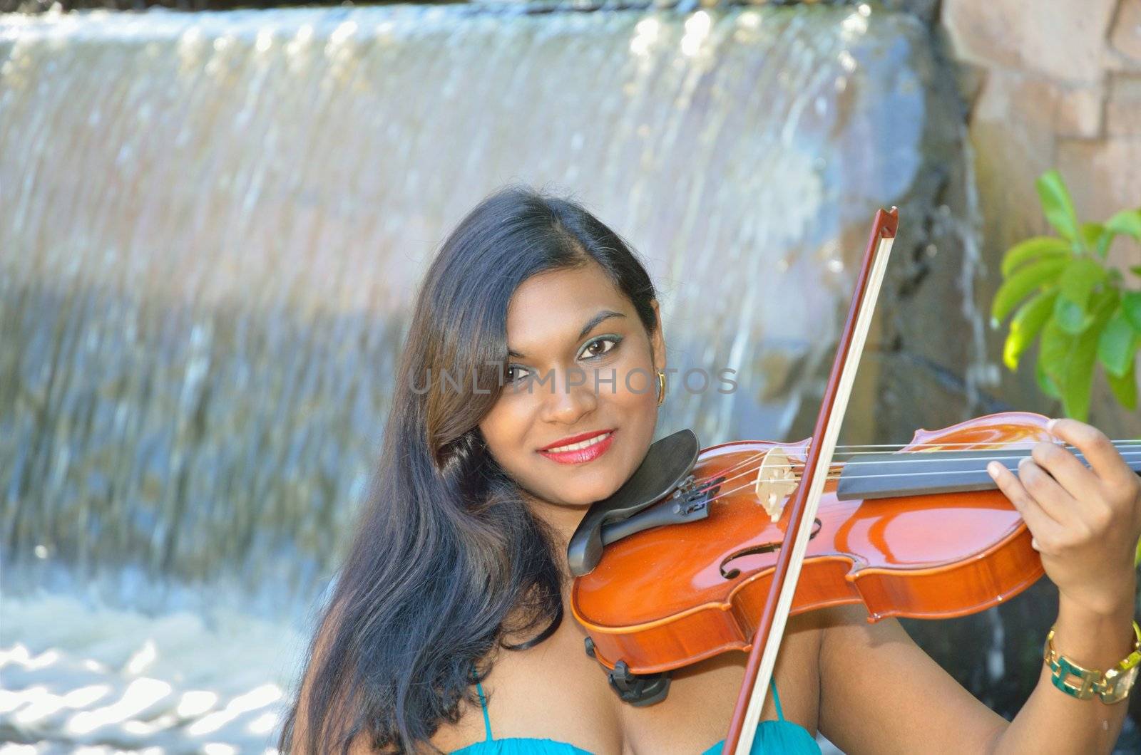 Attractive brunette musician providing live music in the park on her violin