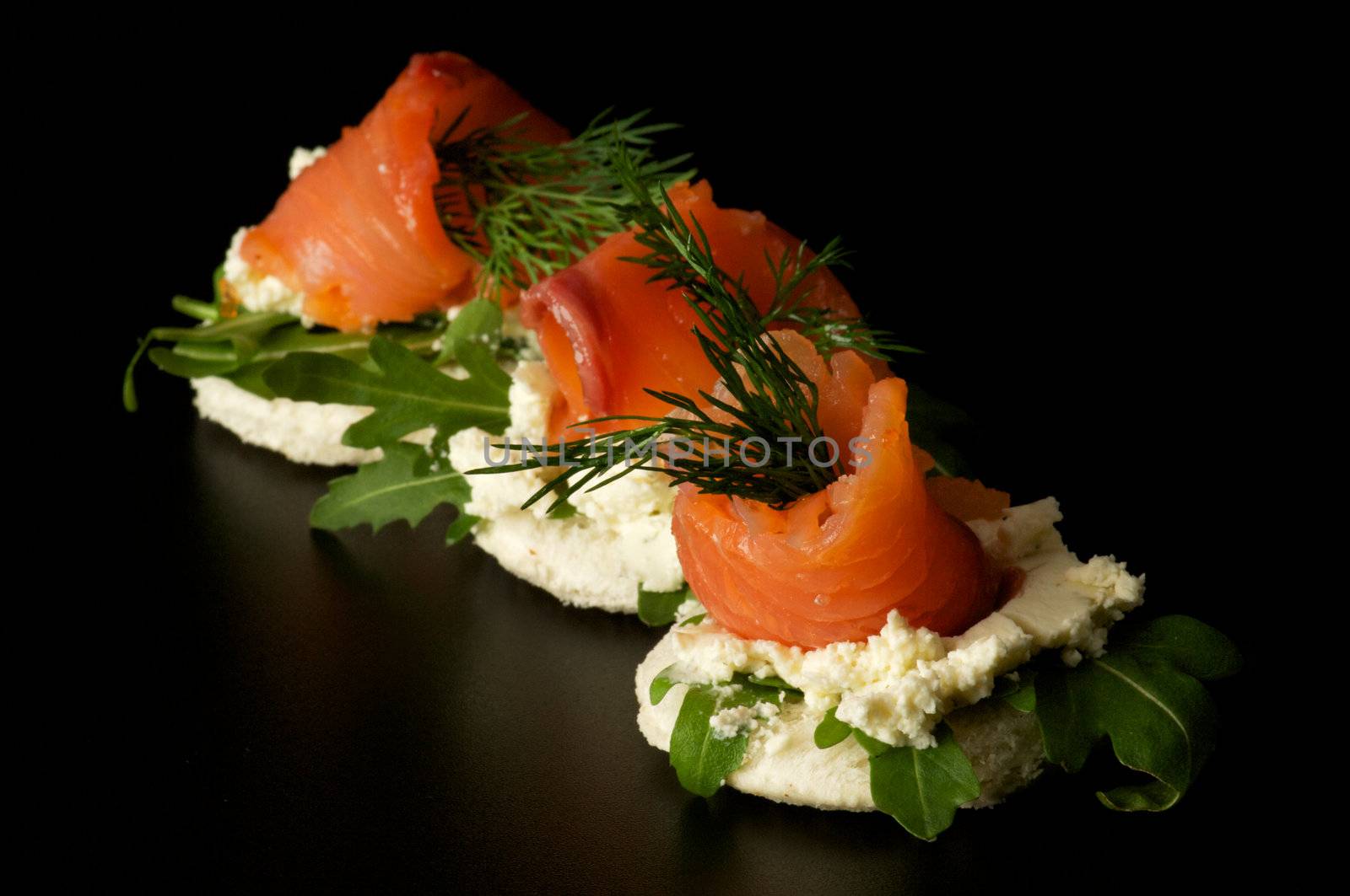 Appetizers Smoked salmon with dill on cracker isolated on black background