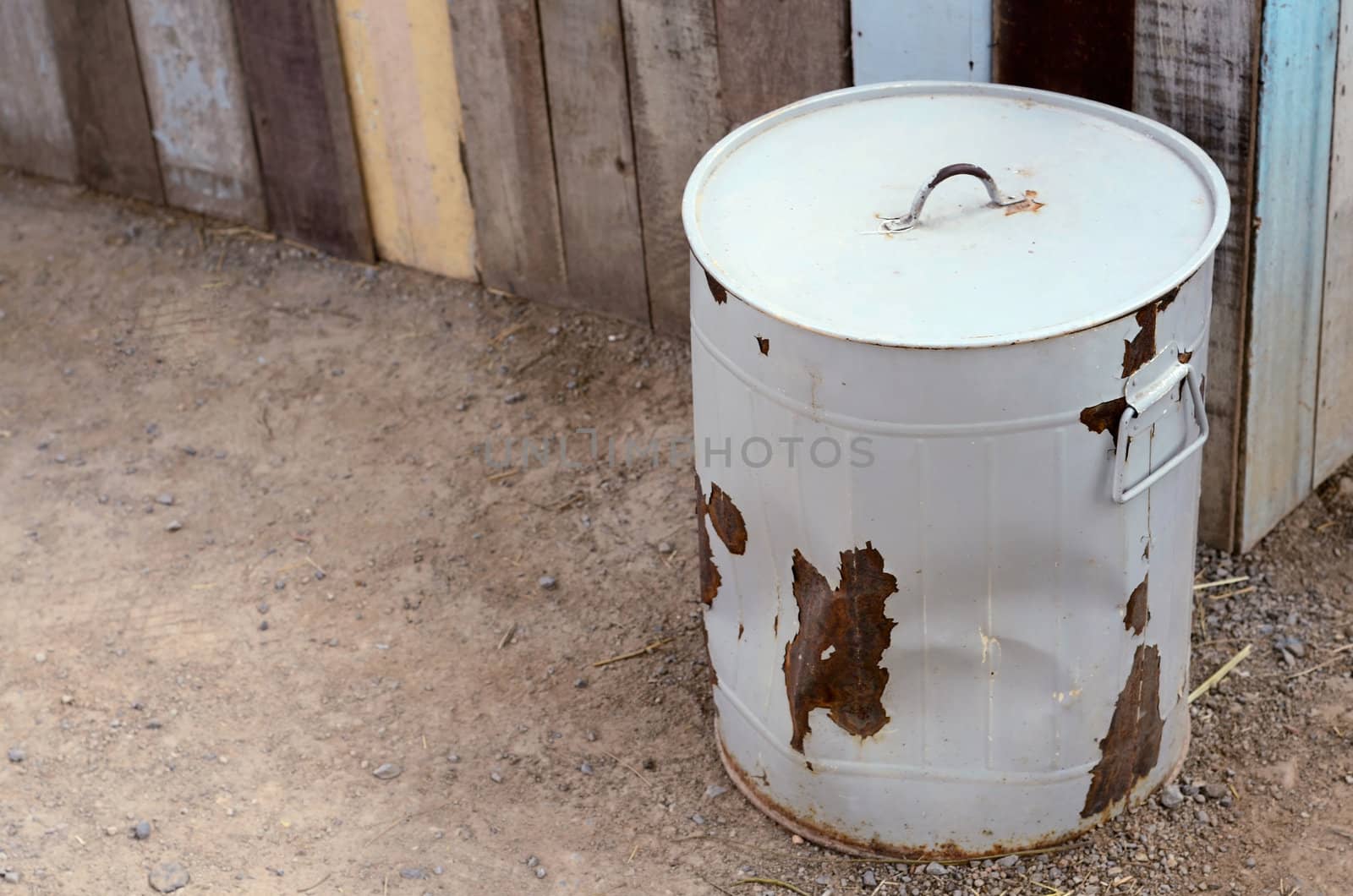 Round gray steel rust trash with lid on the ground