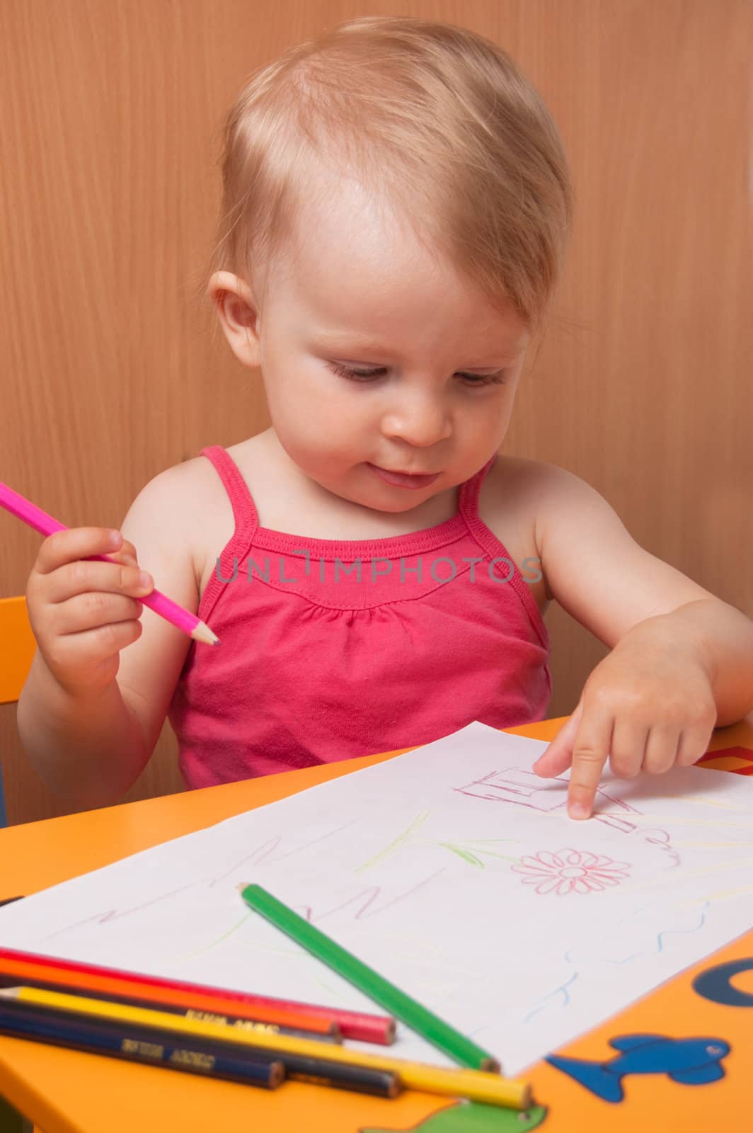 Baby girl drawing with pencils at table