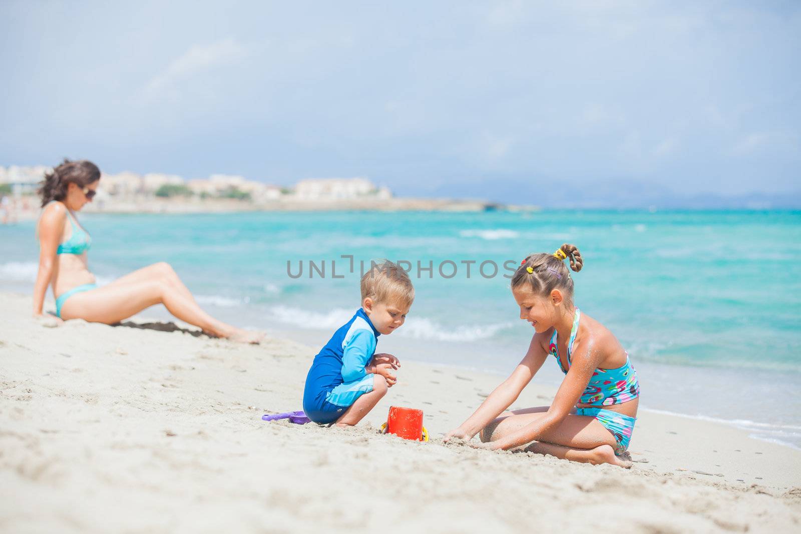 Photo of plaing two kids at beach wis his mother